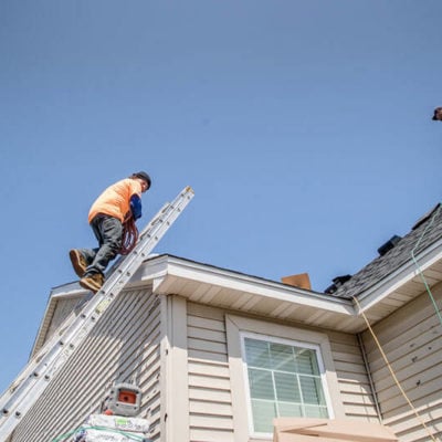 northface construction employee climbing latter on house