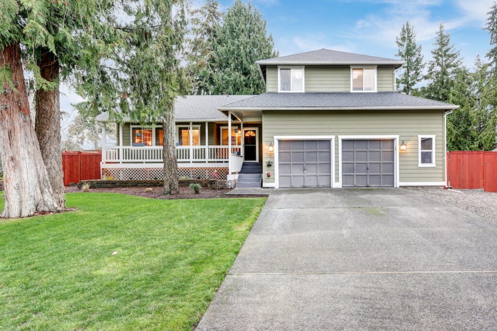 Beautiful curb appeal of a green siding home with covered front porch.