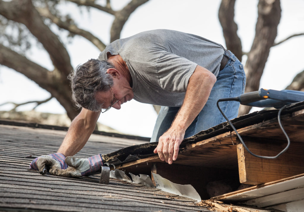 man inspecting damaged roof flashing causing leaks