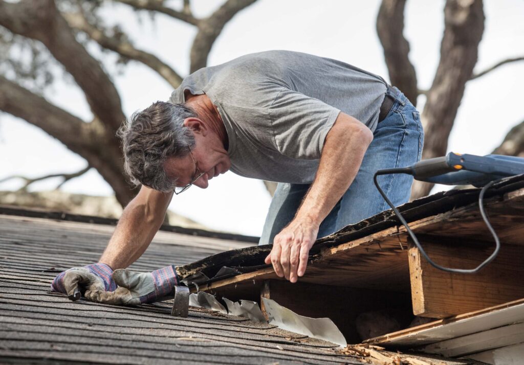 man inspecting damaged roof flashing causing roof leaks