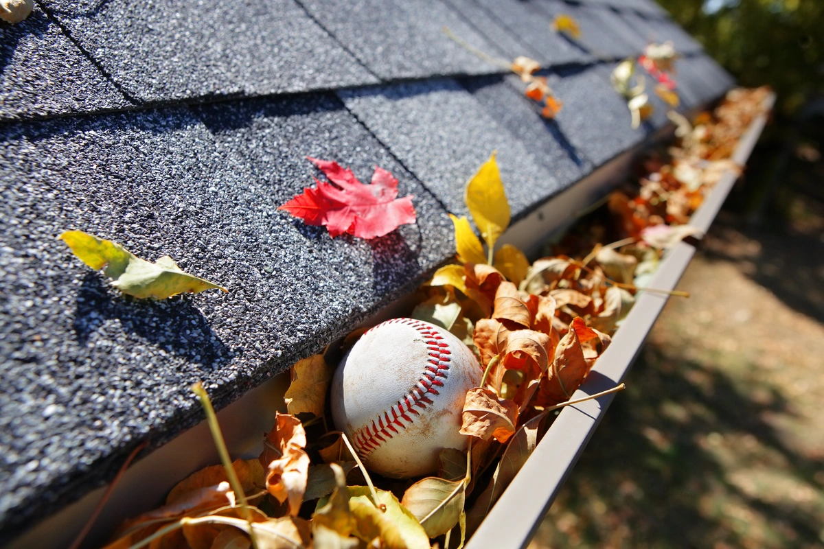house gutters filled with fall leaves and a ball