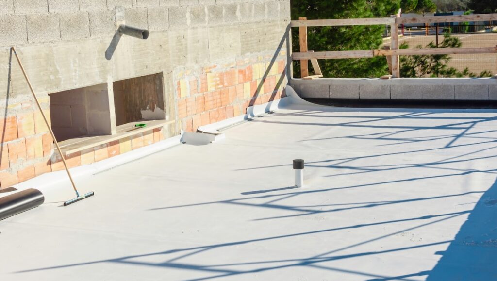 Worker applies tpo membrane roller on roof very carefully.
