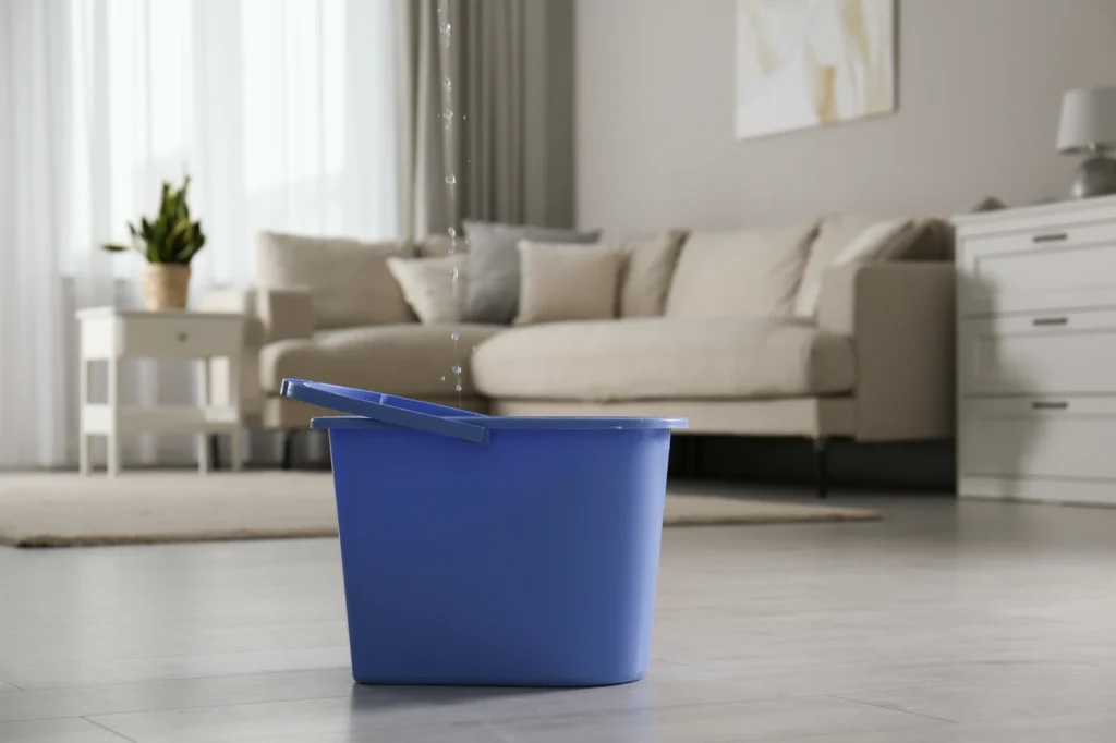 close up of bucket on floor of home dealing with ceiling leak