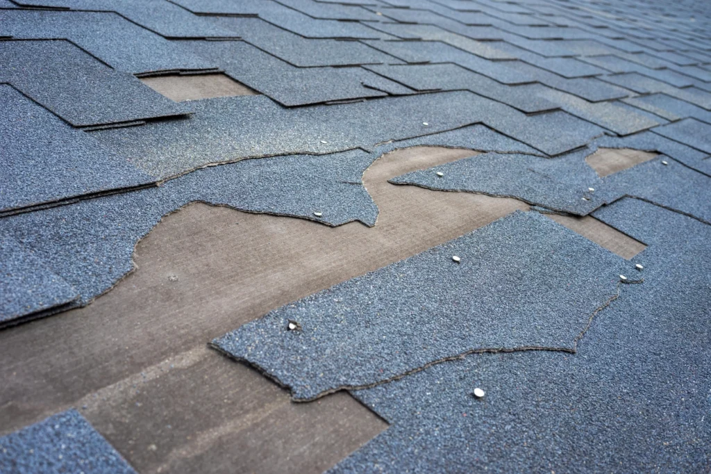 close up of extremely damaged asphalt roof shingles on leaking roof
