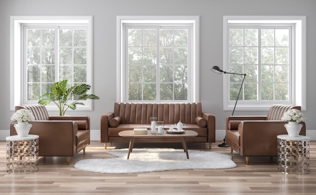 The vintage style living room is decorated with brown-orange leather sofa surrounded by large windows