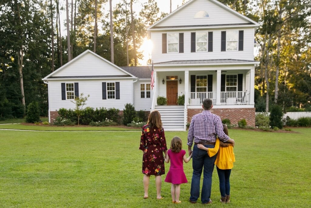 Family of four looking a their large home